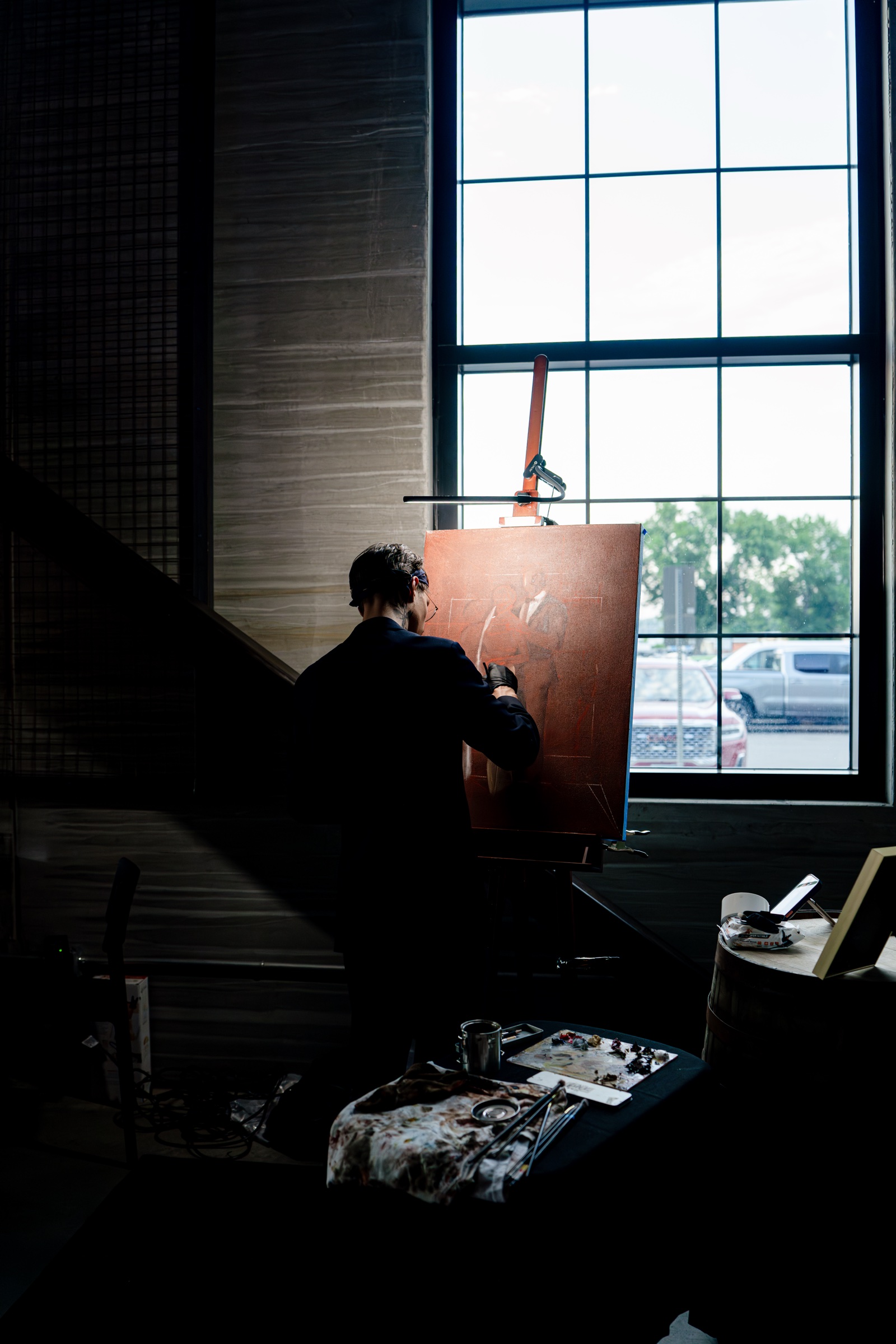 Nicholas Kontz painting beside a tall window during a wedding reception.