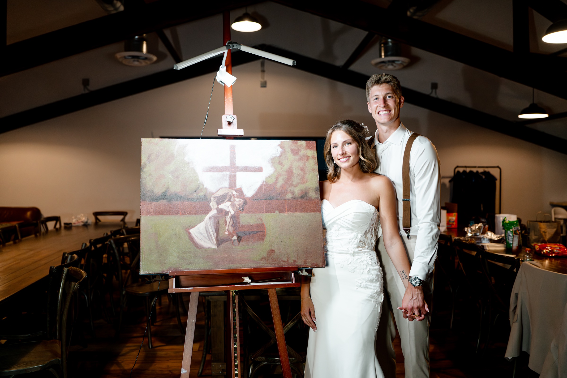 The bride and groom standing beside their live wedding painting.